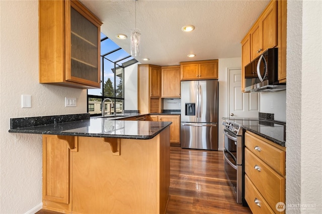 1113 5th Ave S Unit 301, Edmonds, WA 98020 - kitchen featuring stainless steel appliances, a sink, a peninsula, a textured wall, and brown cabinets