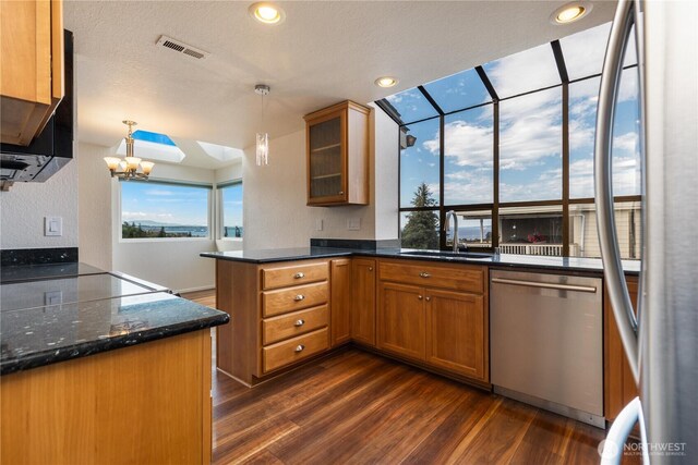 1113 5th Ave S Unit 301, Edmonds, WA 98020 - kitchen with appliances with stainless steel finishes, a sink, dark wood finished floors, brown cabinetry, and a peninsula