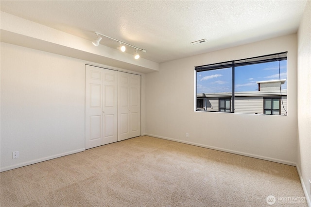 1113 5th Ave S Unit 301, Edmonds, WA 98020 - unfurnished bedroom with carpet, rail lighting, baseboards, a textured ceiling, and a closet