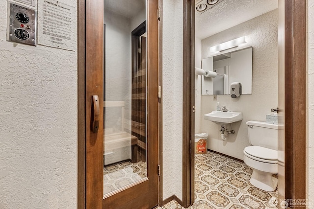 1113 5th Ave S Unit 301, Edmonds, WA 98020 - bathroom featuring a textured wall, toilet, a sink, and baseboards