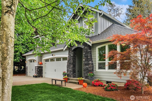 view of front of home with board and batten siding, an attached garage, driveway, and roof with shingles