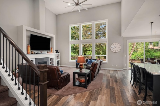 living area featuring stairway, a high ceiling, dark wood finished floors, and a healthy amount of sunlight