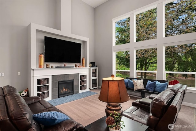 living room with a high ceiling, carpet flooring, and a tile fireplace