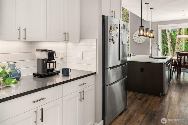 kitchen with dark wood-type flooring, white cabinetry, tasteful backsplash, a sink, and stainless steel appliances