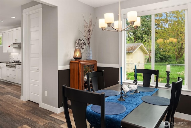 dining space with dark wood-type flooring, baseboards, a healthy amount of sunlight, and an inviting chandelier