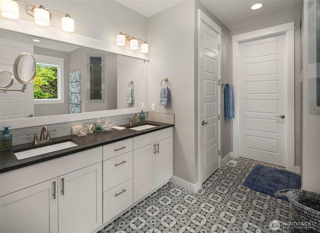 full bath with baseboards, a sink, double vanity, and recessed lighting