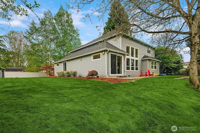rear view of property with fence and a yard