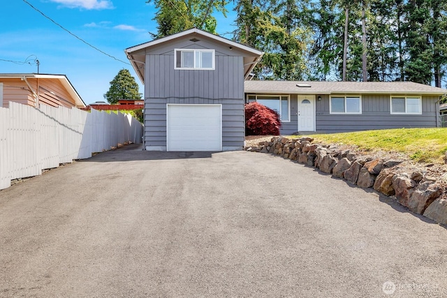 view of front of property featuring fence, a garage, asphalt driveway, and board and batten siding