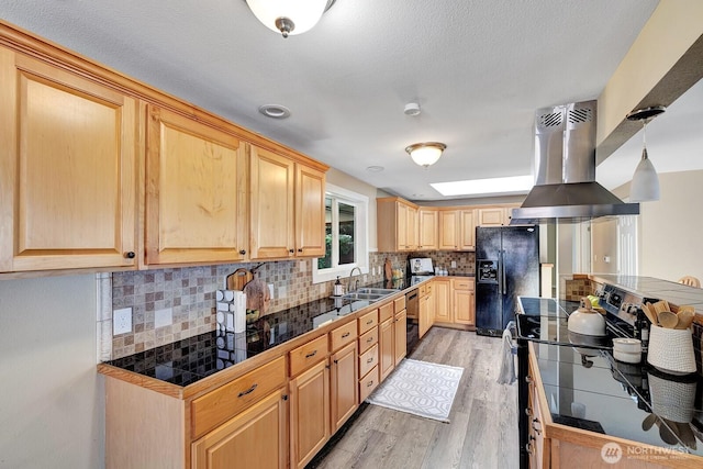 kitchen with island exhaust hood, black appliances, light wood-type flooring, a sink, and light brown cabinets
