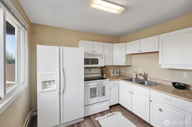 kitchen featuring white appliances, a sink, healthy amount of natural light, and dark wood-type flooring