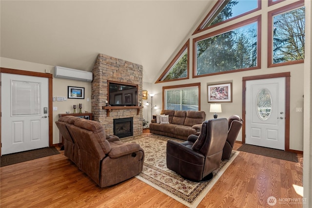 81 N Fawn Dr, Hoodsport, WA 98548 - living area with high vaulted ceiling, a stone fireplace, light wood-style flooring, baseboards, and a wall unit AC