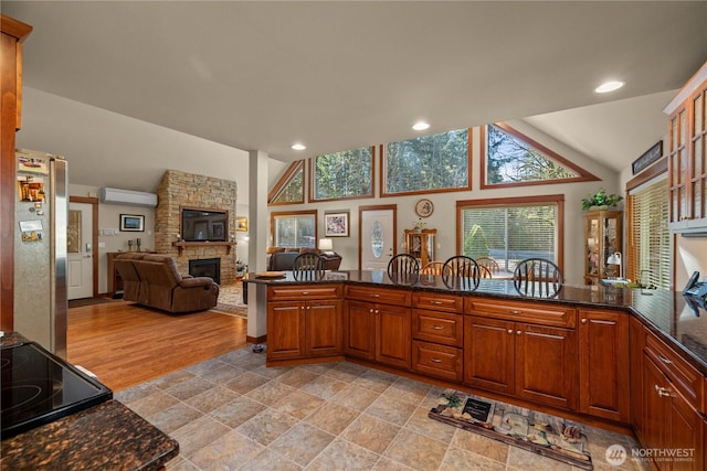 81 N Fawn Dr, Hoodsport, WA 98548 - kitchen with a healthy amount of sunlight, a fireplace, vaulted ceiling, a wall mounted air conditioner, and freestanding refrigerator