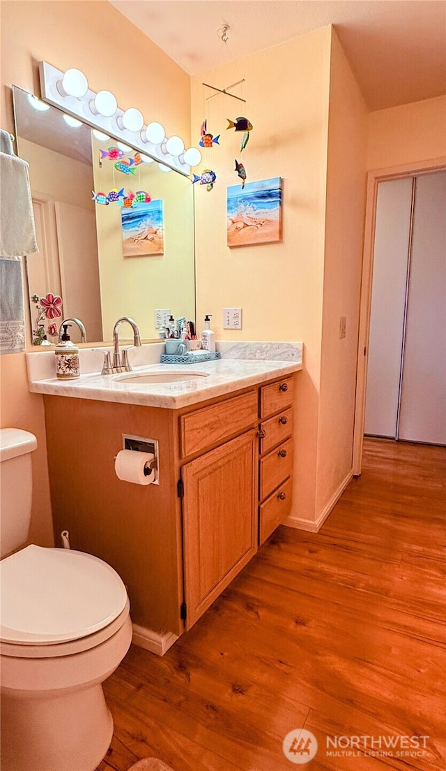 half bath featuring toilet, wood finished floors, and vanity