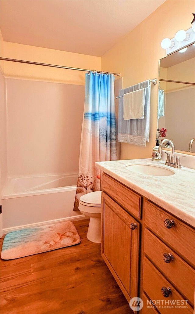 full bath with shower / bath combo with shower curtain, wood finished floors, toilet, and vanity