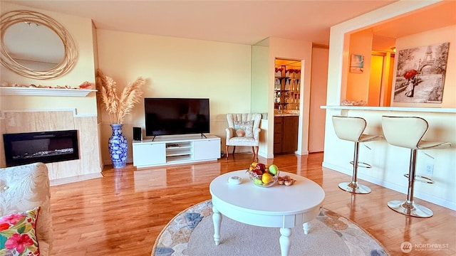 living room with baseboards, a glass covered fireplace, and wood finished floors