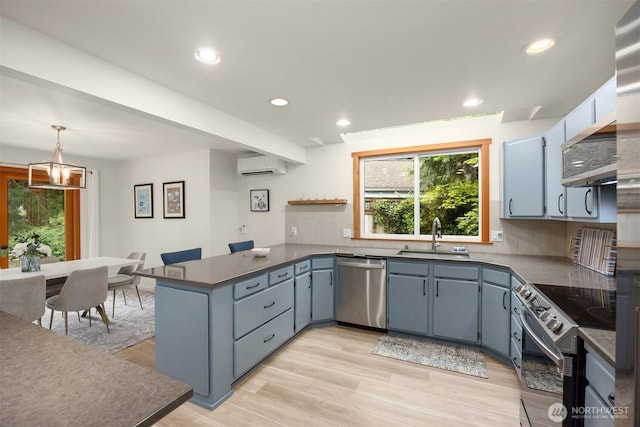 kitchen featuring appliances with stainless steel finishes, tasteful backsplash, a sink, an AC wall unit, and a peninsula