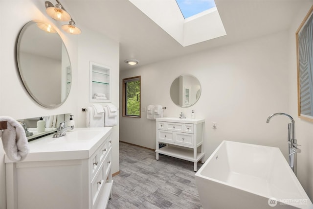 bathroom featuring a skylight, wood finished floors, two vanities, a sink, and a soaking tub