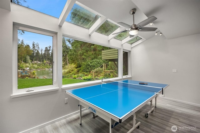 rec room featuring baseboards, a ceiling fan, wood finished floors, and rail lighting