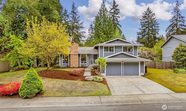 tri-level home featuring fence, roof with shingles, a front lawn, a chimney, and driveway
