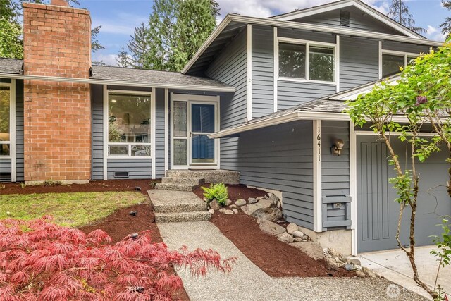 tri-level home featuring roof with shingles and a chimney