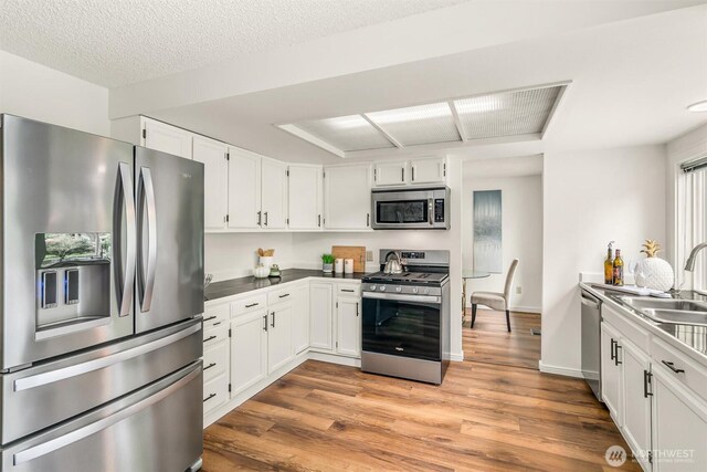 kitchen featuring a sink, appliances with stainless steel finishes, white cabinets, and light wood finished floors