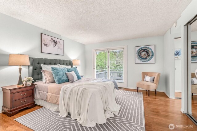 bedroom with light wood-style floors, access to outside, and a textured ceiling