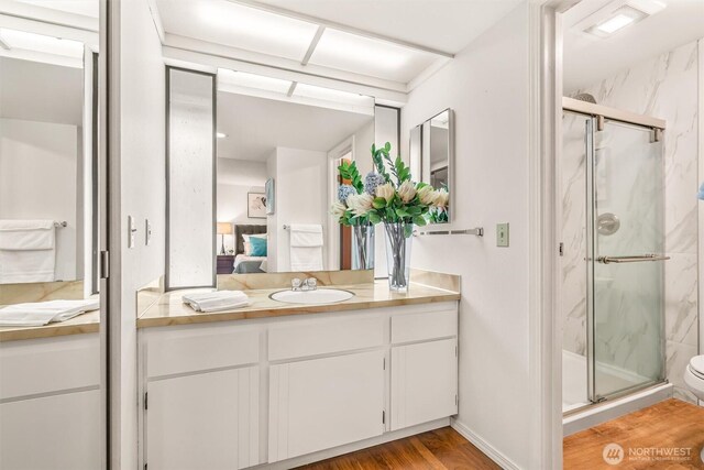 full bathroom with a marble finish shower, vanity, wood finished floors, and connected bathroom