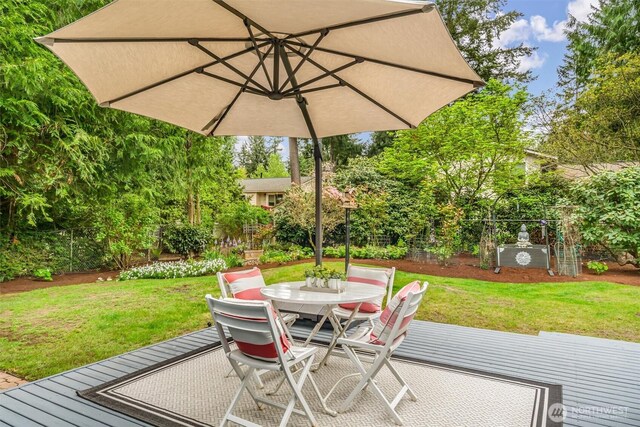 view of patio featuring fence, a wooden deck, and outdoor dining area