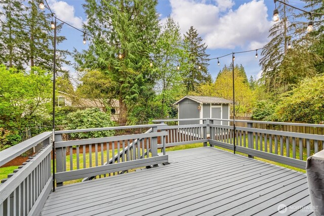 wooden terrace featuring a fenced backyard, an outbuilding, and a storage shed