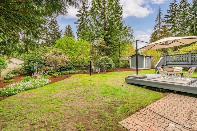view of yard featuring a fenced backyard, a wooden deck, an outbuilding, and a shed