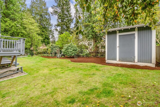 view of yard with an outbuilding, fence, a storage shed, and a wooden deck