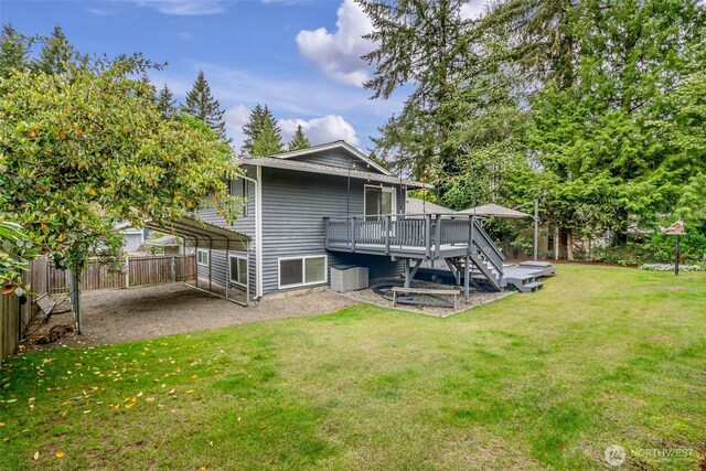 back of property featuring fence, a deck, stairway, a lawn, and a detached carport
