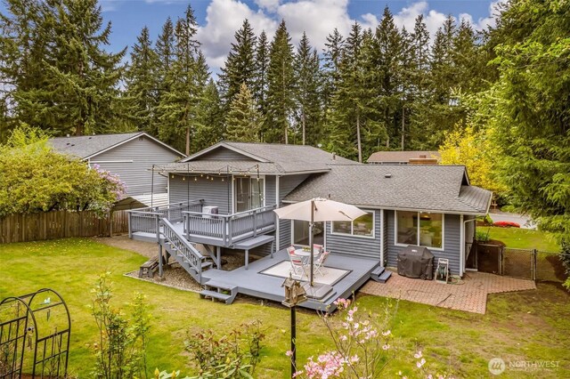 back of property featuring a wooden deck, a fenced backyard, a shingled roof, a gate, and a lawn