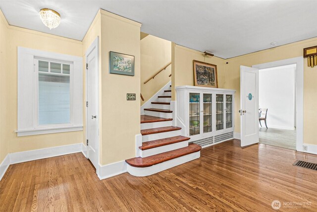 stairway featuring visible vents, baseboards, and wood finished floors