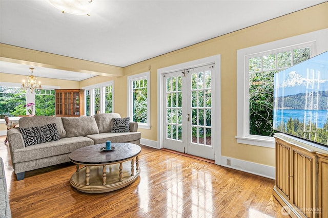 living room featuring baseboards, a notable chandelier, and light wood finished floors