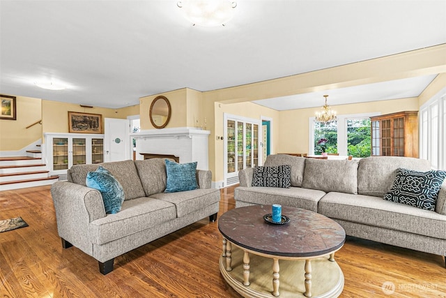 living area featuring stairs, wood finished floors, and a notable chandelier