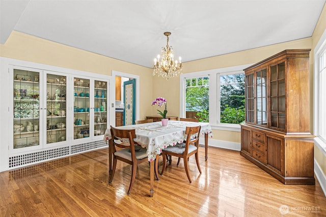 dining room with an inviting chandelier, baseboards, and light wood finished floors
