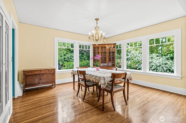 dining area featuring baseboards, an inviting chandelier, plenty of natural light, and wood finished floors