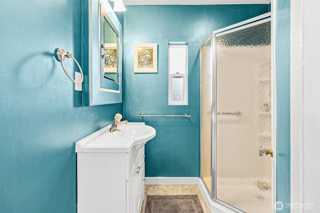 full bath with vanity, baseboards, and a shower stall