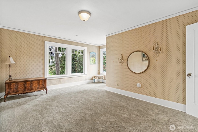 unfurnished living room featuring carpet flooring, wallpapered walls, ornamental molding, and baseboards