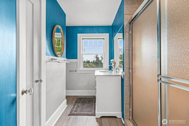 full bath featuring vanity, baseboards, a stall shower, and wood finished floors