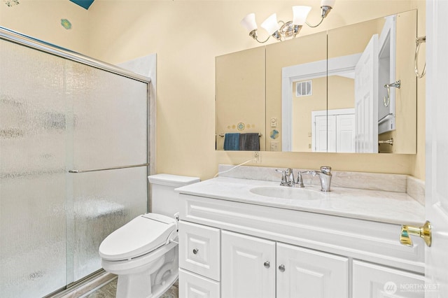 full bathroom with vanity, a shower stall, toilet, and visible vents