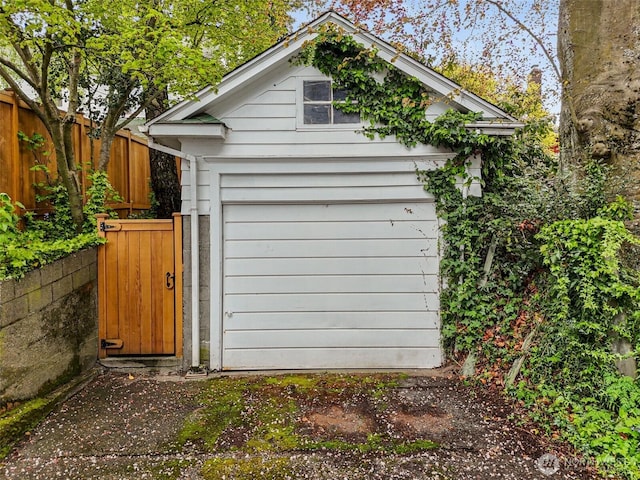 view of outbuilding with a gate, fence, and an outbuilding