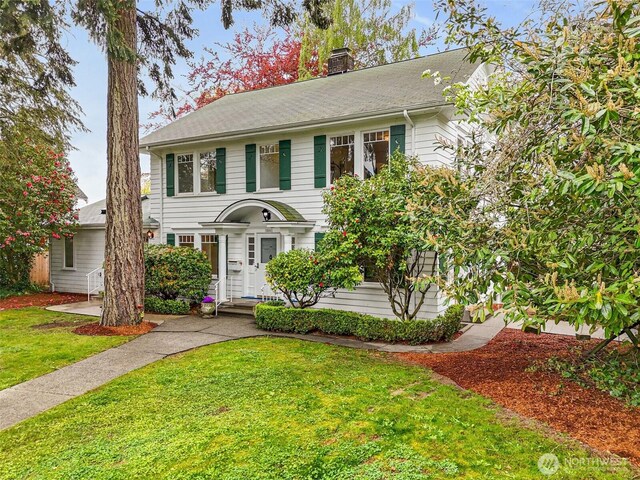 colonial-style house with a chimney and a front yard