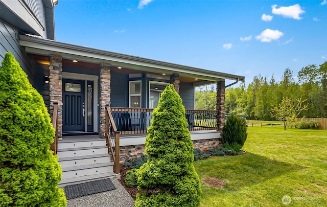 property entrance with a yard, a porch, fence, and stone siding