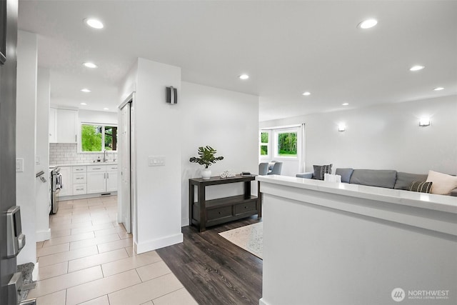 corridor featuring recessed lighting, a sink, and wood finished floors