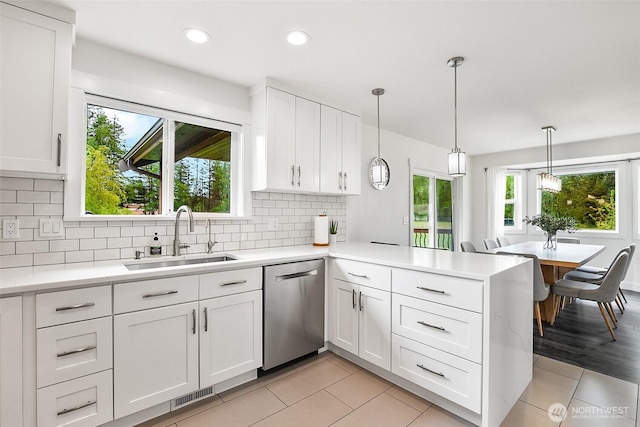 kitchen featuring visible vents, stainless steel dishwasher, a sink, light countertops, and a peninsula
