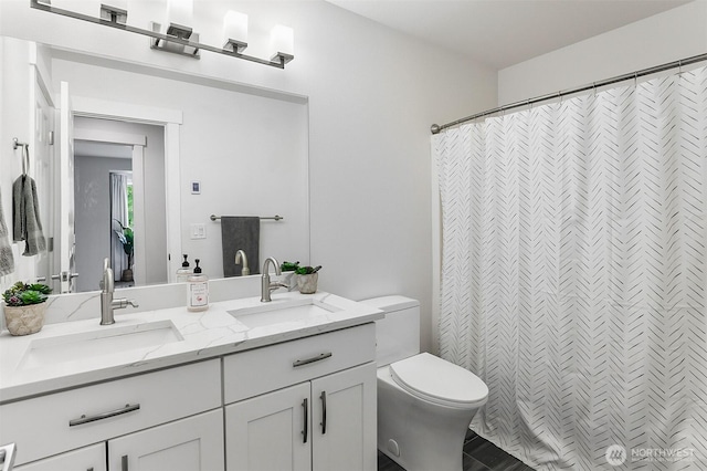 bathroom with double vanity, toilet, a shower with curtain, and a sink