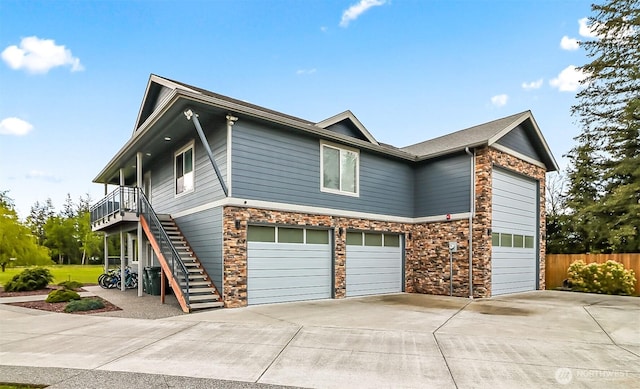 view of front of house with driveway, a garage, fence, stairs, and stone siding