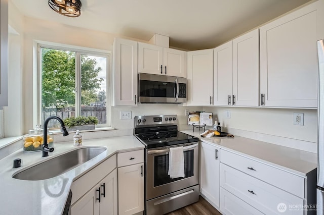 kitchen featuring white cabinets, appliances with stainless steel finishes, a sink, and light countertops